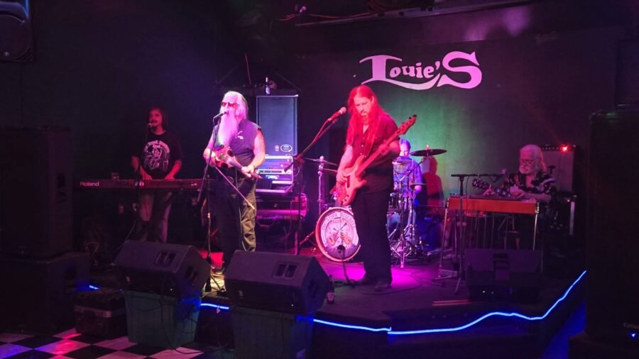 A live band on stage under the Louie's sign