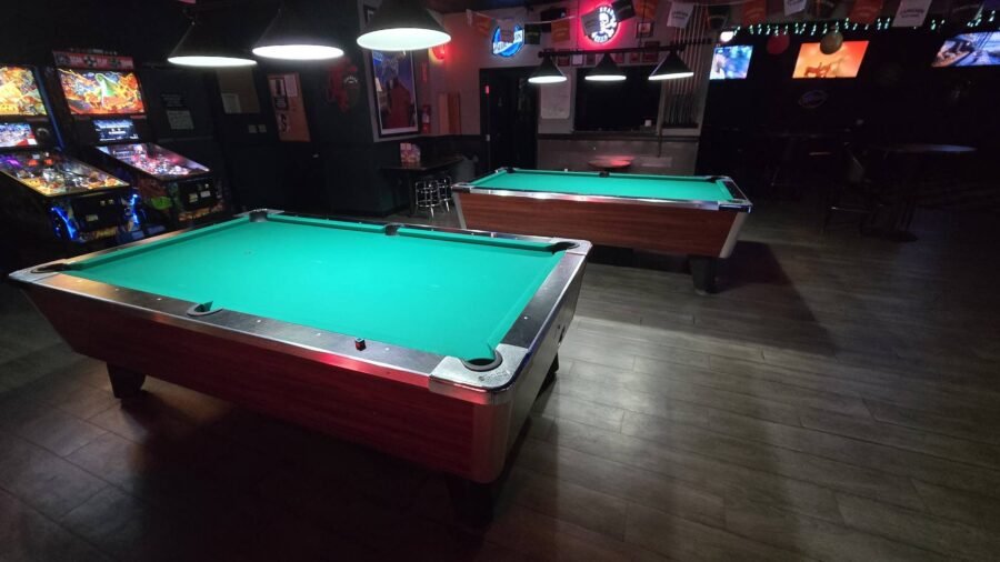 Pool table with arcade and pinball machines behind